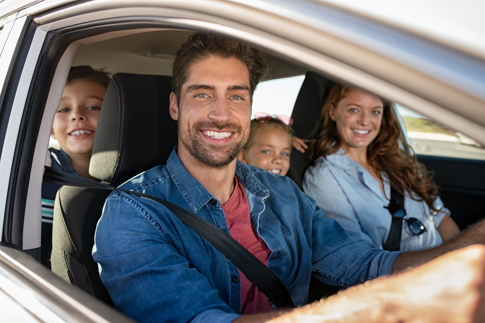 Happy family with children in vehicle demonstrating family car safety and comfort