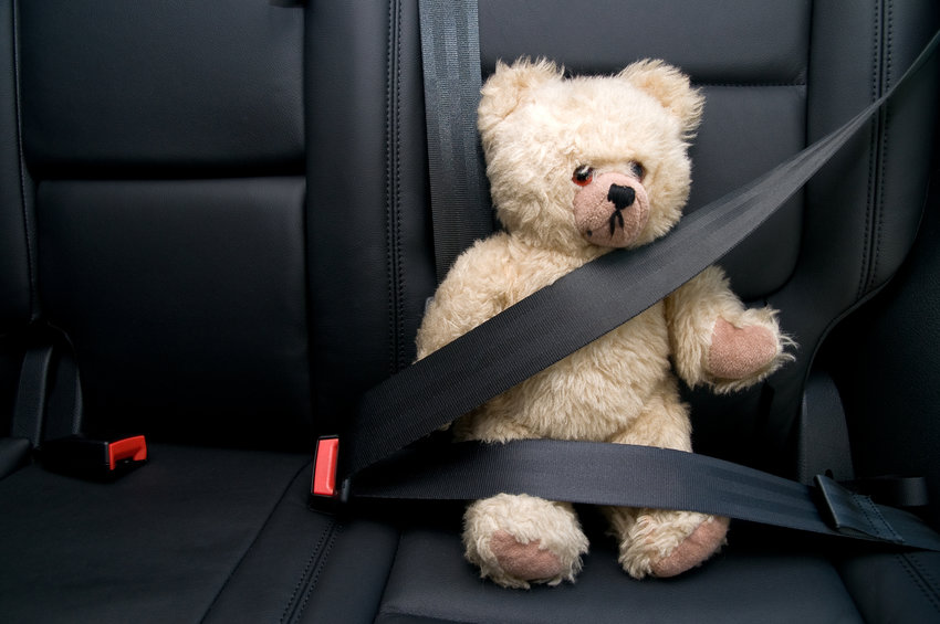 Teddy bear secured with seatbelt demonstrating child safety and family vehicle protection